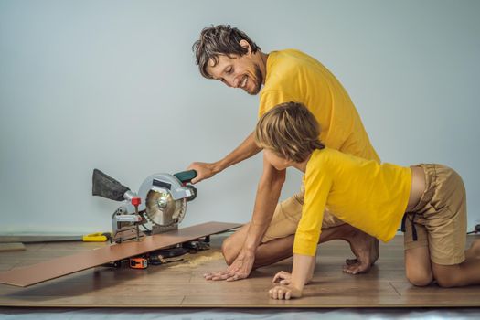 Father and son installing new wooden laminate flooring on a warm film floor. Infrared floor heating system under laminate floor.