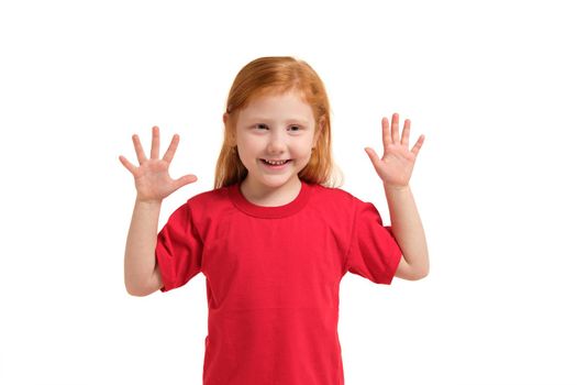 Little girl smiling with his arms up. 5 years old girl surprised with smile and hands near her hands. Red-haired girl in a red T-shirt isolated on white background
