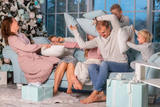 Big Happy family with many kids having fun and pillow fight under the Christmas tree. Christmas family eve, christmas mood concept