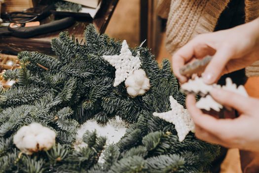 Girl decorates a wreath of natural branches of fir. Creation of a Christmas wreath from natural fir and Christmas decorations. Master class on creating a Christmas wreath.