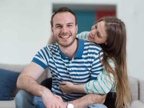 young handsome couple enjoys hugging on the sofa in their luxury home villa