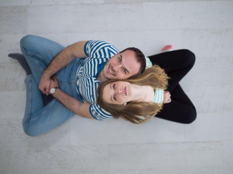 top view of Cheerful young couple sitting with back to each other on floor
