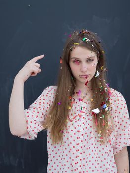 beautiful young woman celebrating new year and chrismas party while blowing confetti decorations to camera isolated over gray background