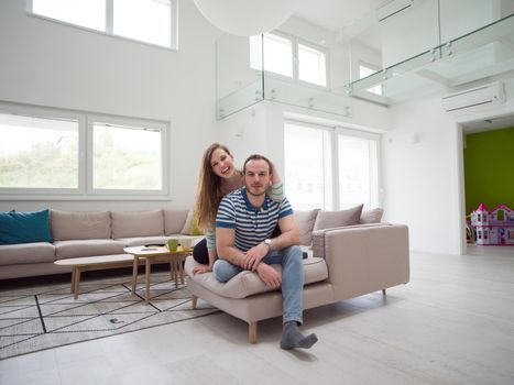 young handsome couple enjoys hugging on the sofa in their luxury home villa