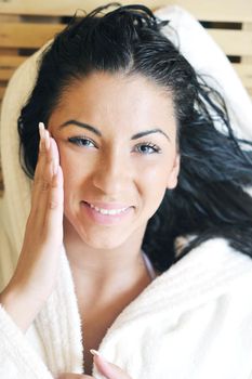 Pretty Young woman take a steam bath treatment at finish wooden sauna while wearing white towel
