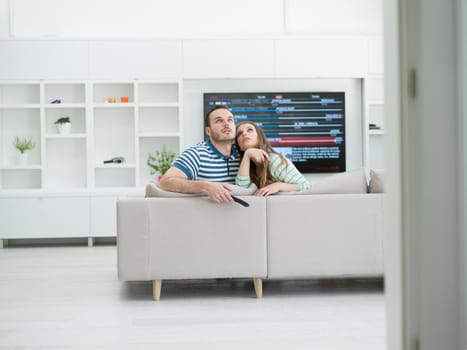 Young couple on the sofa watching television together in their luxury home