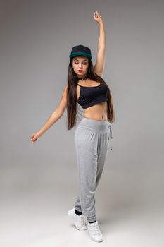 Modern dancer poses in front of the gray studio background. Modern dance styles, dancehall, jazz funk, hip hop