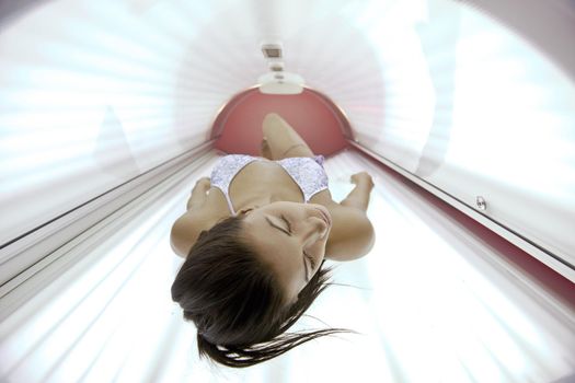 Beautiful young woman have tanning skin treatment in modern solarium