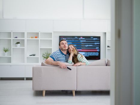 Young couple on the sofa watching television together in their luxury home