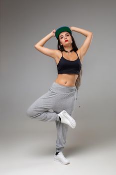Modern dancer poses in front of the gray studio background. Modern dance styles, dancehall, jazz funk, hip hop