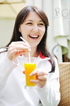 young woman drink juice outdoor in bright restaurant garden at spring
