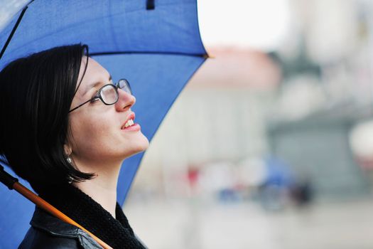 one young happy woman walking in cyti with rainy weater and blue umbrella