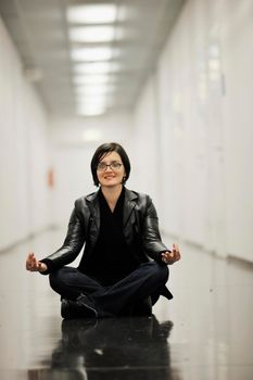 young casual woman sitting and precticing yoga indoor on abstract location