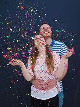 handsome young couple celebrating new year and chrismas party while blowing confetti decorations to camera isolated over gray background