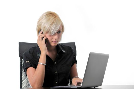 One young business blonde woman working in office on laptop and talking on cellphone, isolated image