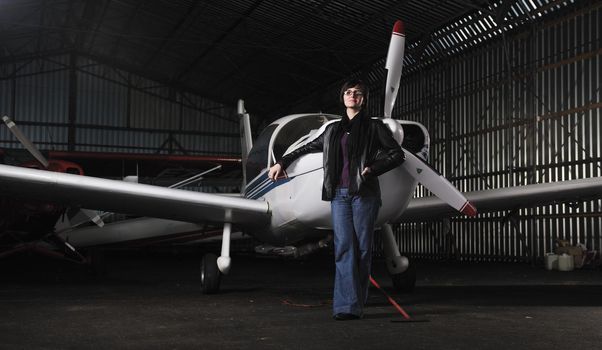 beautiful young woman model in fashion clothes posing in front of old private airplane 