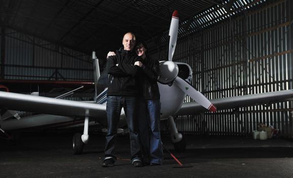 beautiful and happy young couple  posing in front of an old retro private propeler airplane and representing happines wealt and rich life concept