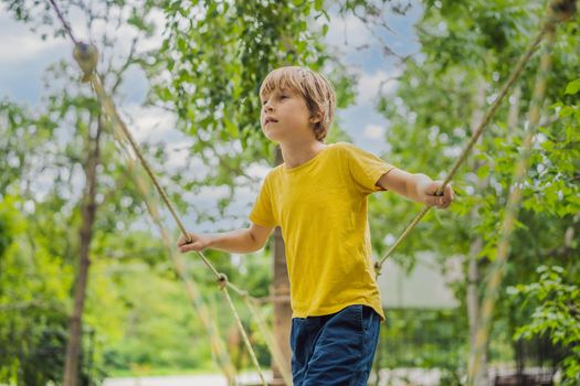 Little boy in a rope park. Active physical recreation of the child in the fresh air in the park. Training for children.