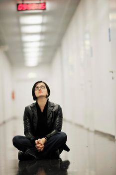 young casual woman sitting and precticing yoga indoor on abstract location