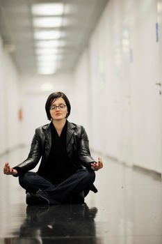 young casual woman sitting and precticing yoga indoor on abstract location