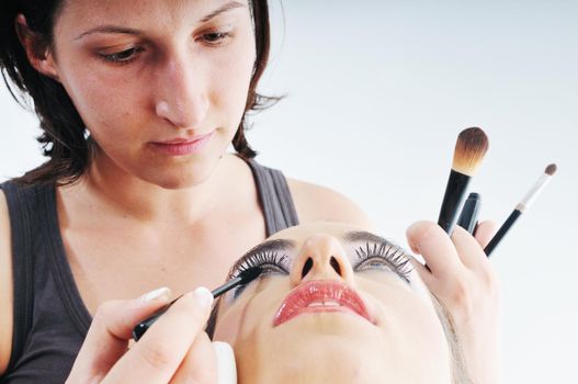 makeup treatment with professional makeup artist and beautiful brunette woman  isolated on white in studio