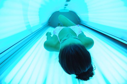 Beautiful young woman have tanning skin treatment in modern solarium