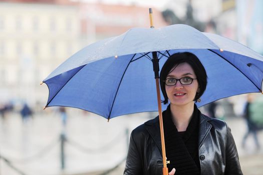 one young happy woman walking in cyti with rainy weater and blue umbrella