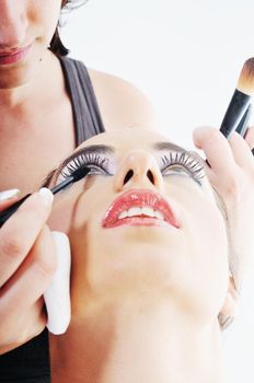 makeup treatment with professional makeup artist and beautiful brunette woman  isolated on white in studio