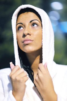 Pretty Young woman take a steam bath treatment at finish wooden sauna while wearing white towel