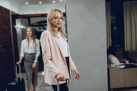 Two young women in formal clothes entering hotel lobby. Business trip concept