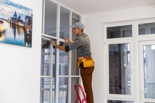 Construction worker installing metal profile for interior partition wall, while building a new house or renovation process, viewed from his back