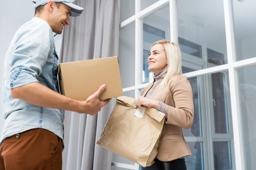 Happy deliverer carrying packages while making home delivery to his customer