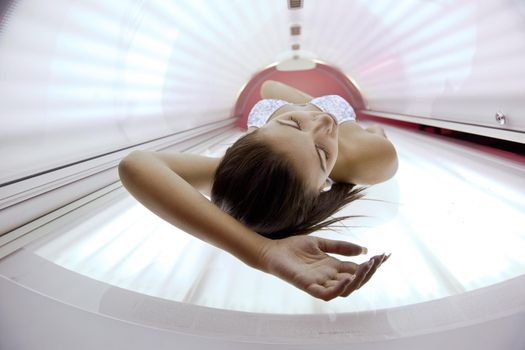 Beautiful young woman have tanning skin treatment in modern solarium