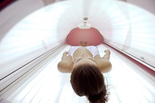 Beautiful young woman have tanning skin treatment in modern solarium