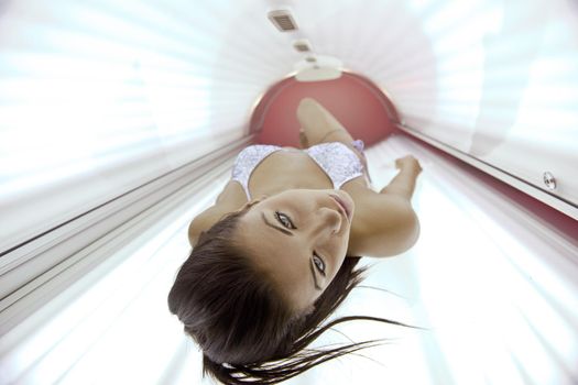 Beautiful young woman have tanning skin treatment in modern solarium