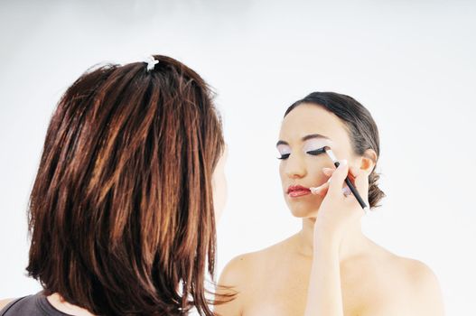 makeup treatment with professional makeup artist and beautiful brunette woman  isolated on white in studio