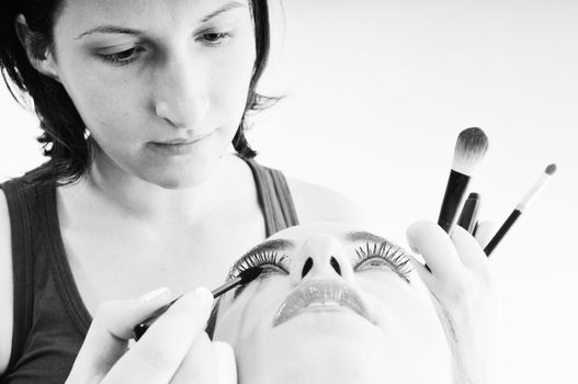 makeup treatment with professional makeup artist and beautiful brunette woman  isolated on white in studio