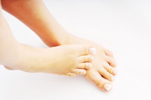 young woman bare foot with makeup nails islated on white