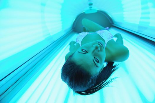 Beautiful young woman have tanning skin treatment in modern solarium