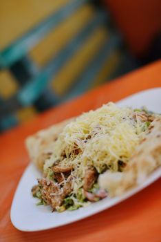 woman eat tasty chicken salad with fresh vegetables and cheese in retro kitchen