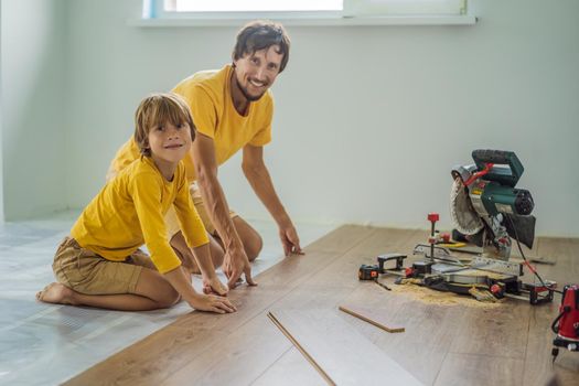 Father and son installing new wooden laminate flooring on a warm film floor. Infrared floor heating system under laminate floor.