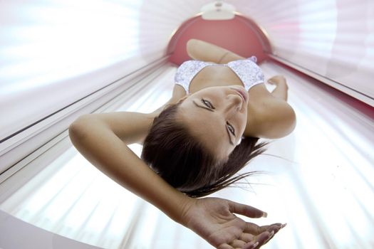 Beautiful young woman have tanning skin treatment in modern solarium