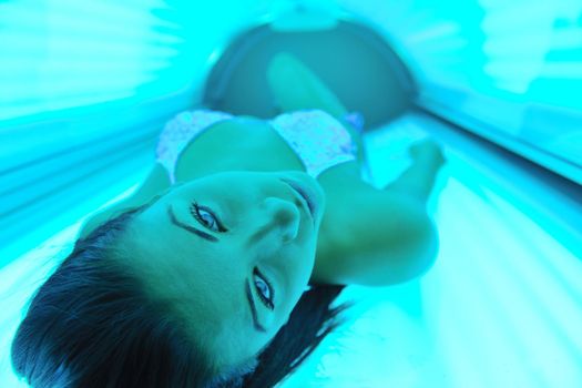 Beautiful young woman have tanning skin treatment in modern solarium