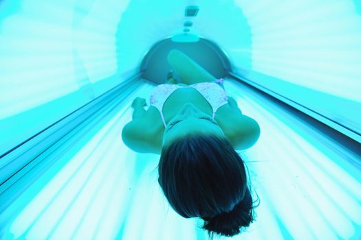 Beautiful young woman have tanning skin treatment in modern solarium