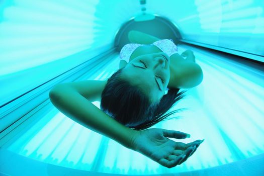 Beautiful young woman have tanning skin treatment in modern solarium