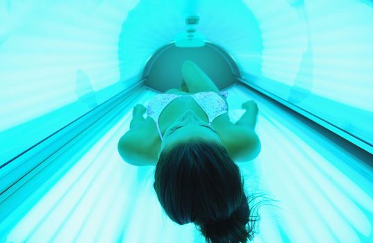 Beautiful young woman have tanning skin treatment in modern solarium