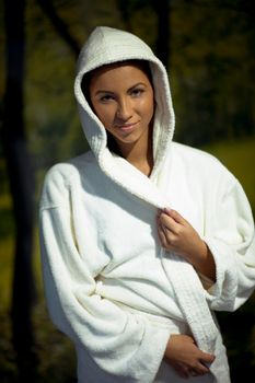 Pretty Young woman take a steam bath treatment at finish wooden sauna while wearing white towel