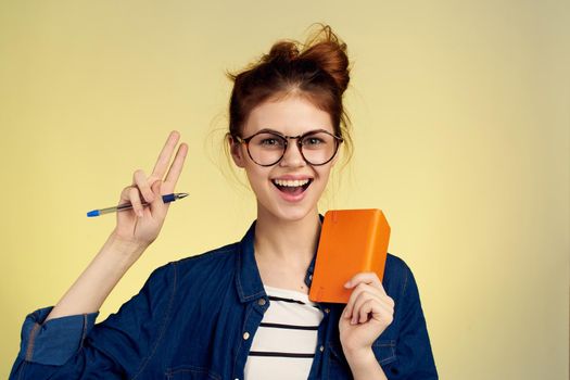 woman student with glasses notepad with pen yellow background. High quality photo