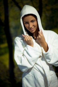 Pretty Young woman take a steam bath treatment at finish wooden sauna while wearing white towel