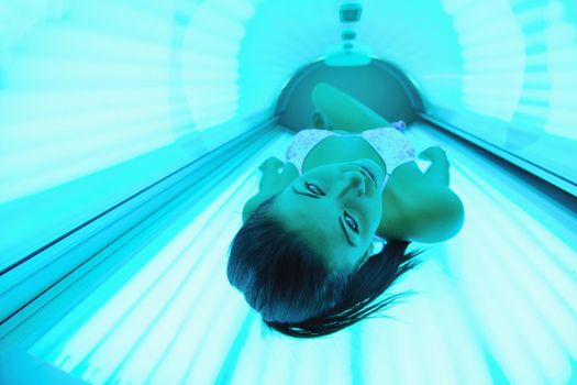 Beautiful young woman have tanning skin treatment in modern solarium